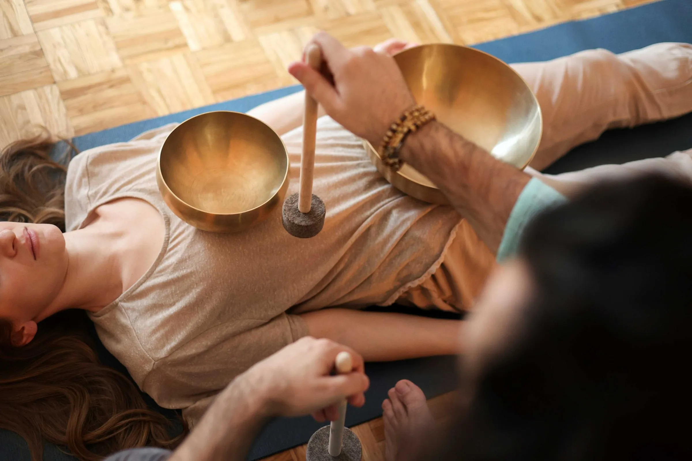 Klangschalen werden auf dem Bauch einer liegenden Person angeschlagen