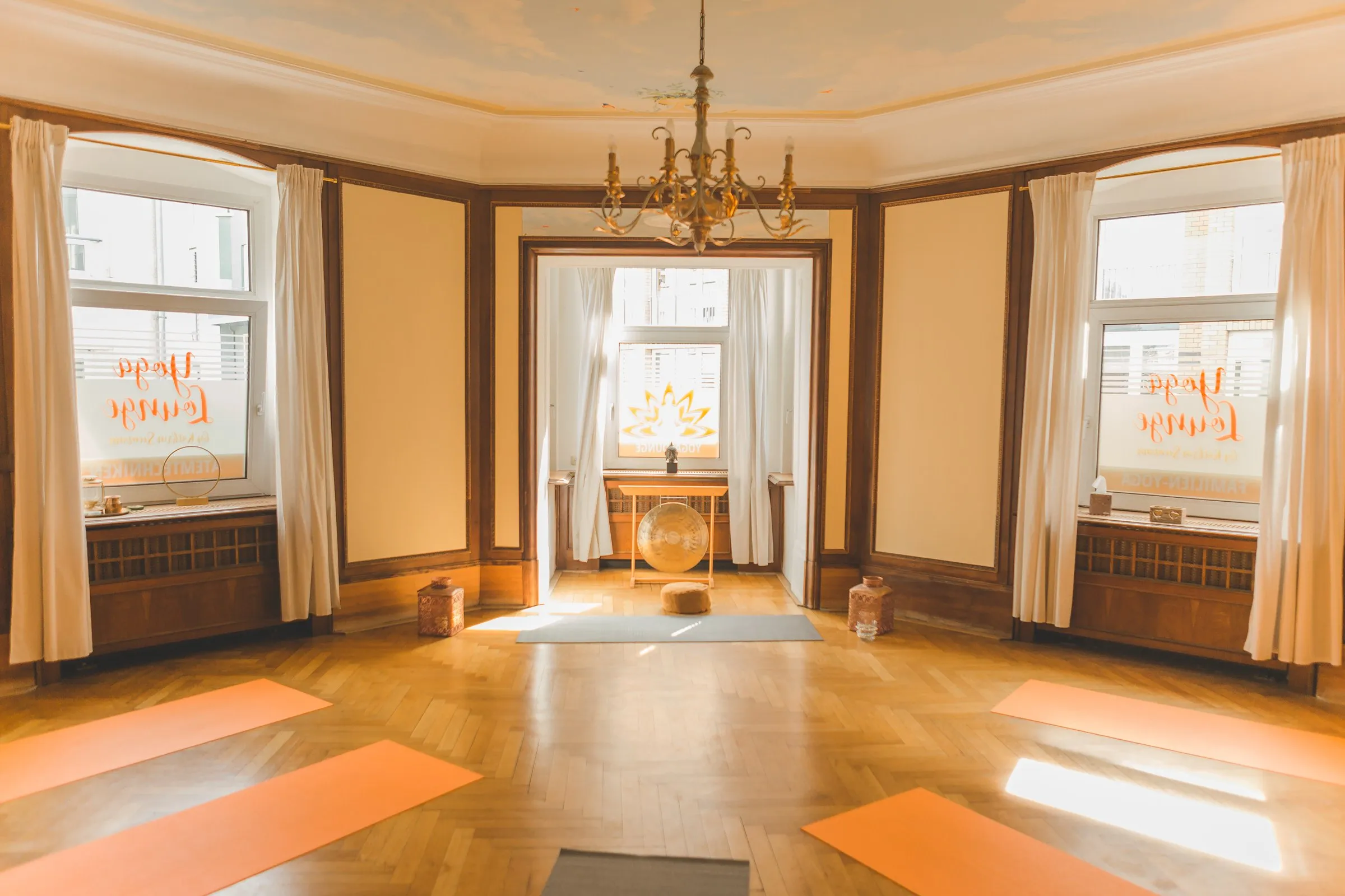 Großer Yogaraum mit Erker, Kronleuchter, hohen Fenstern und Holzboden